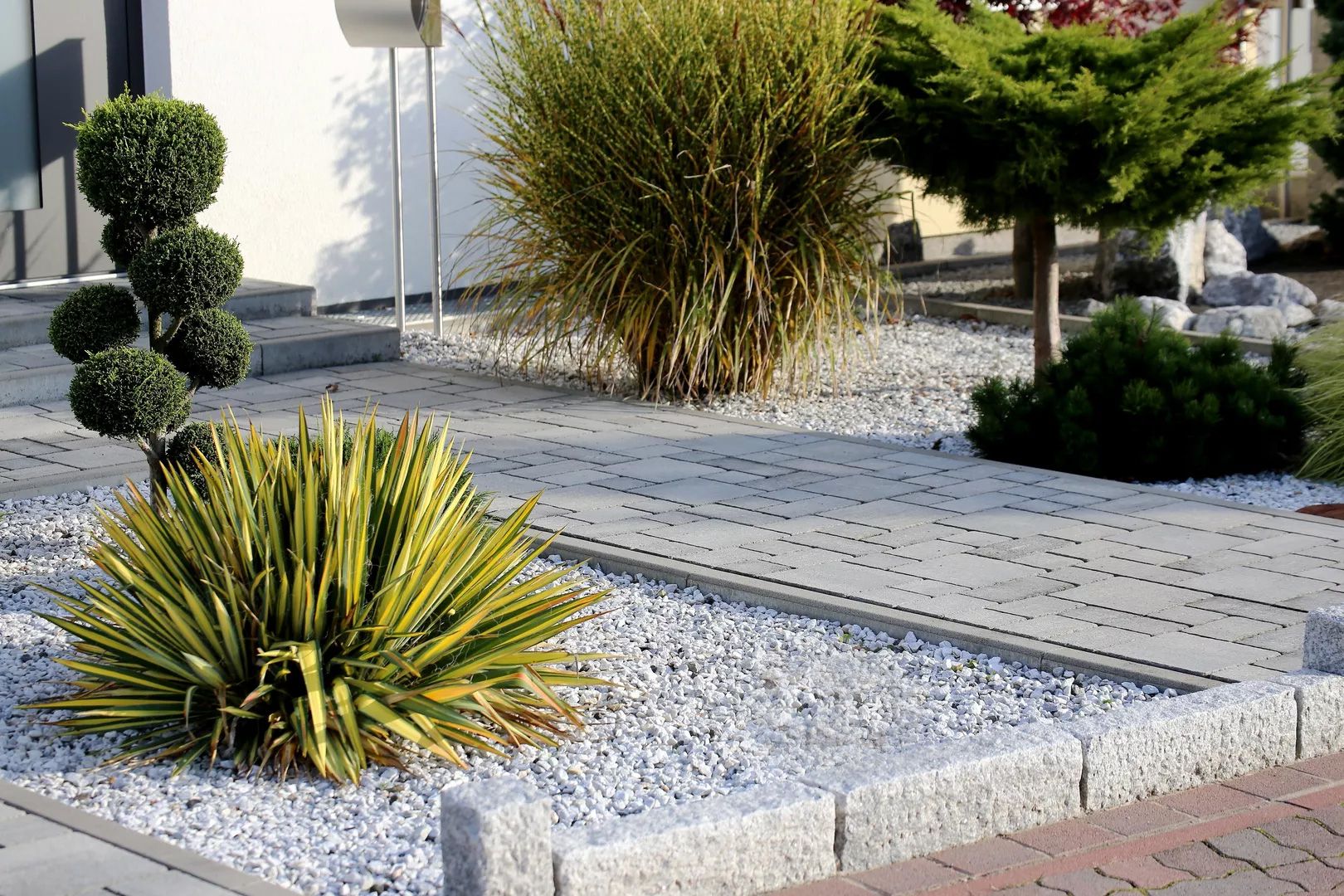 Beet mit weißem Kies und Gräsern